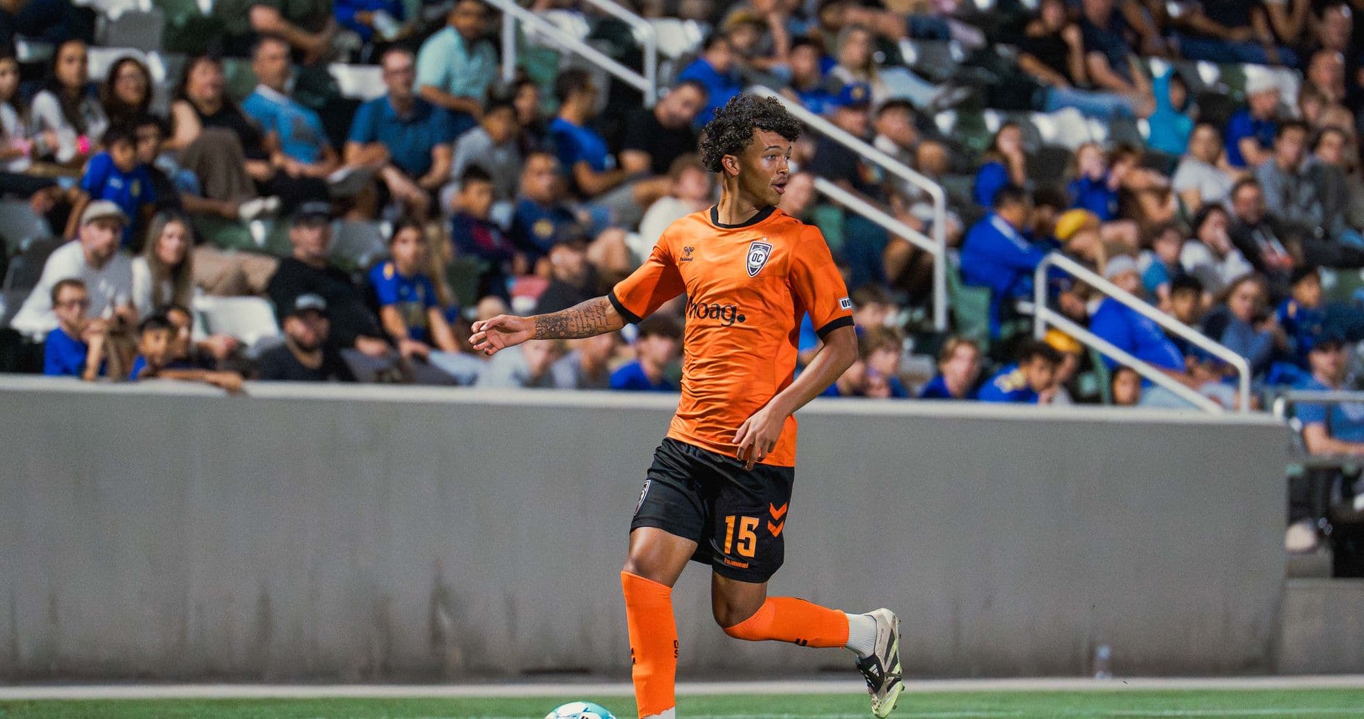 Player in orange jersey dribbling ball on field