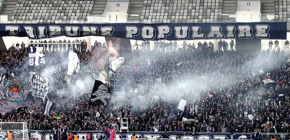 Crowd cheering with flags and smoke during match