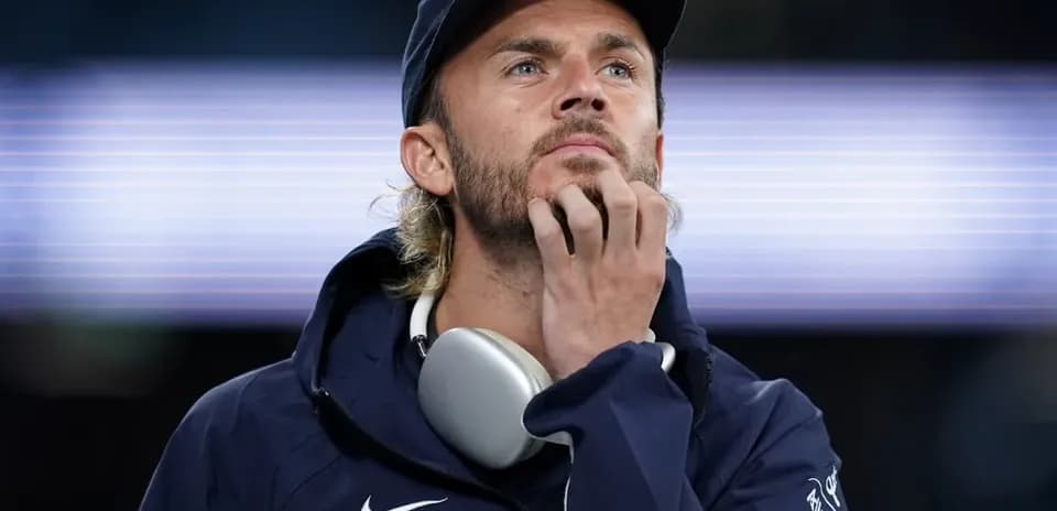 Man in hoodie and cap looking thoughtfully
