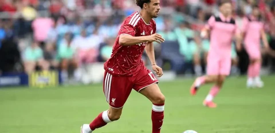 Player in red jersey running with ball during match