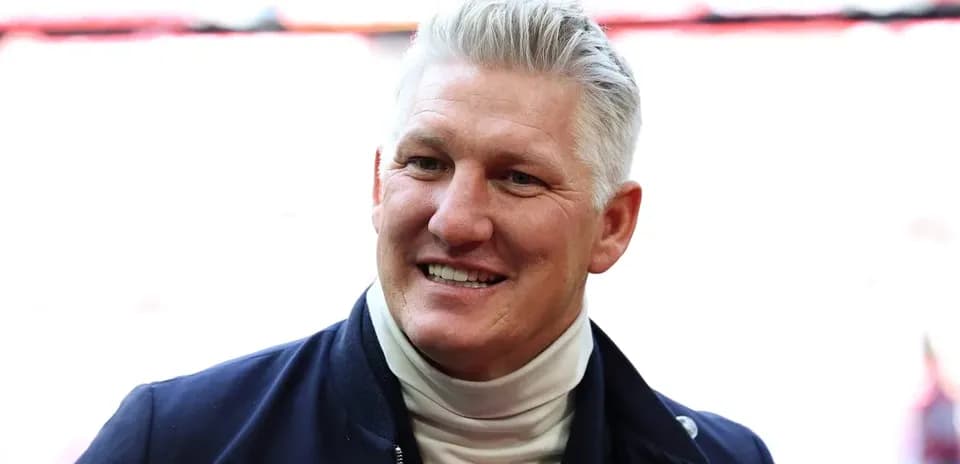 Man smiling in a jacket at stadium entrance