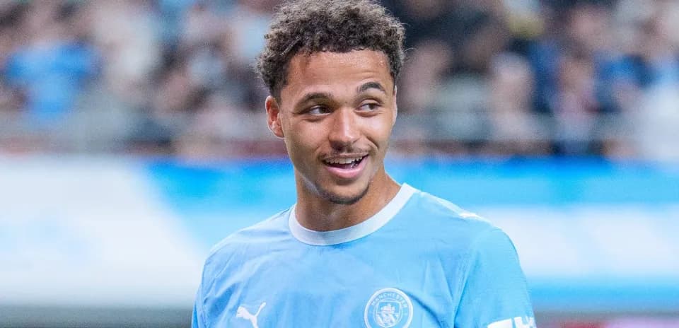 Player in Manchester City jersey smiling during warm-up