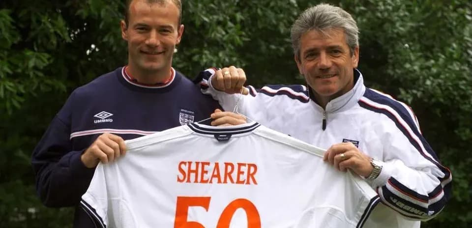 Two men holding an England jersey with 'SHEARER 50'