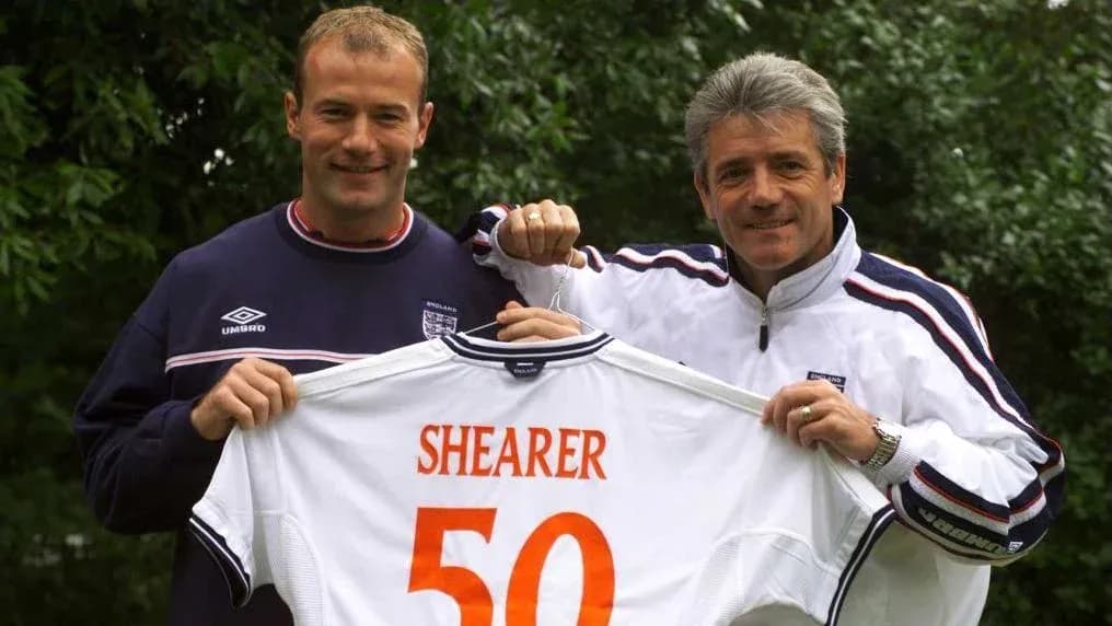 Two men holding an England jersey with 'SHEARER 50'