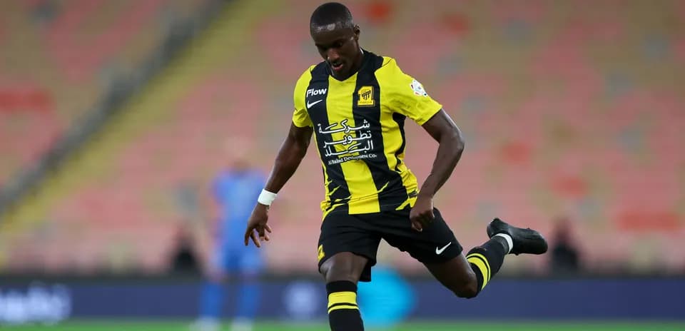 Player in black and yellow kit kicking soccer ball