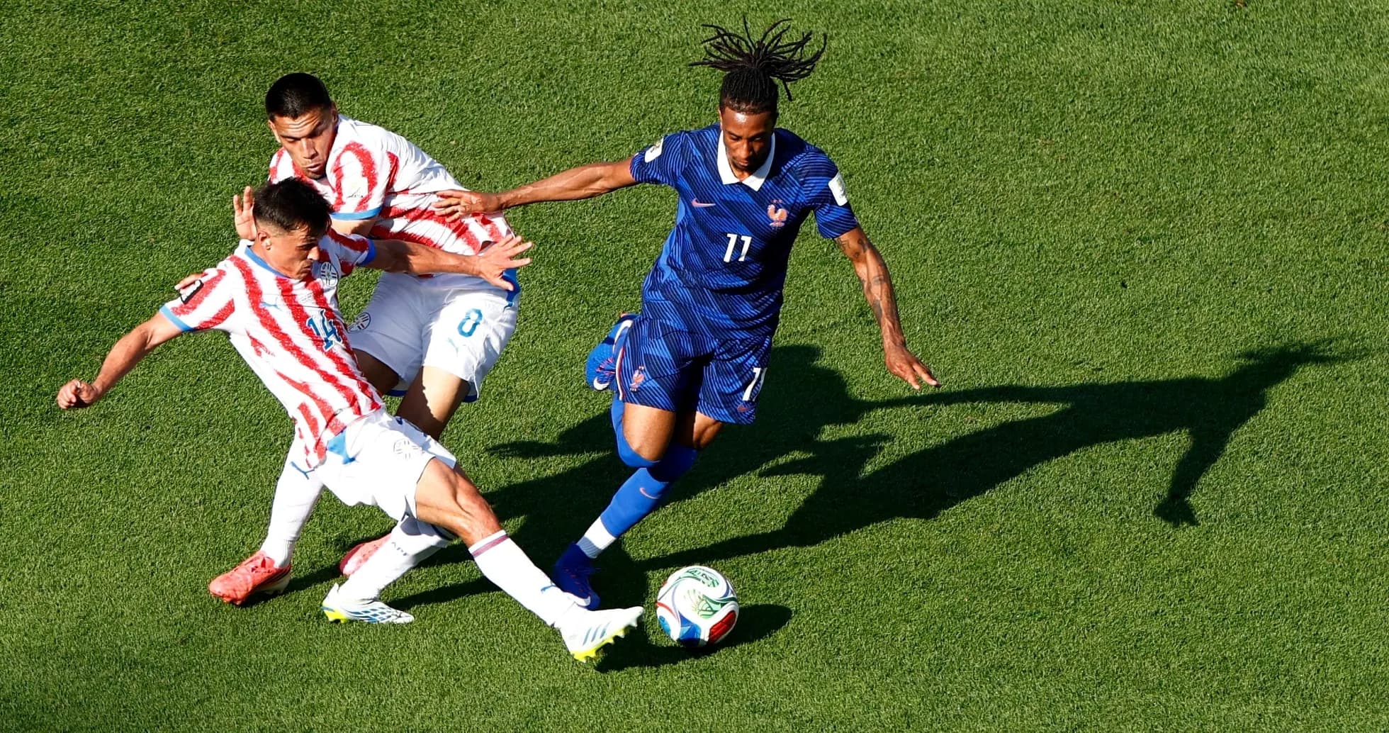 Paraguay player challenges France player for ball