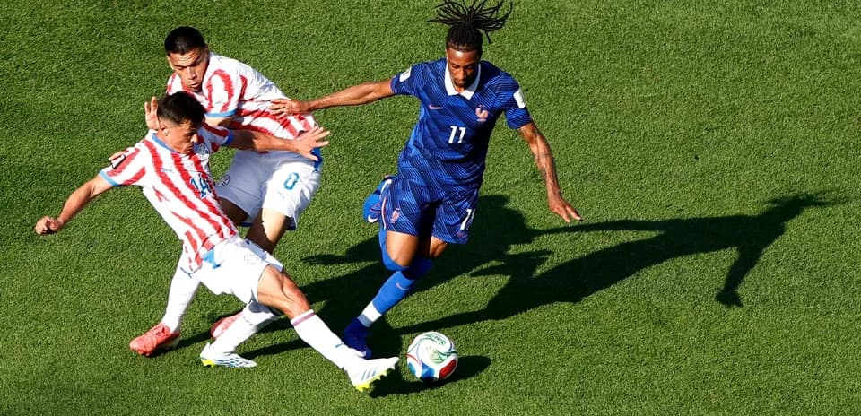Paraguay player challenges France player for ball
