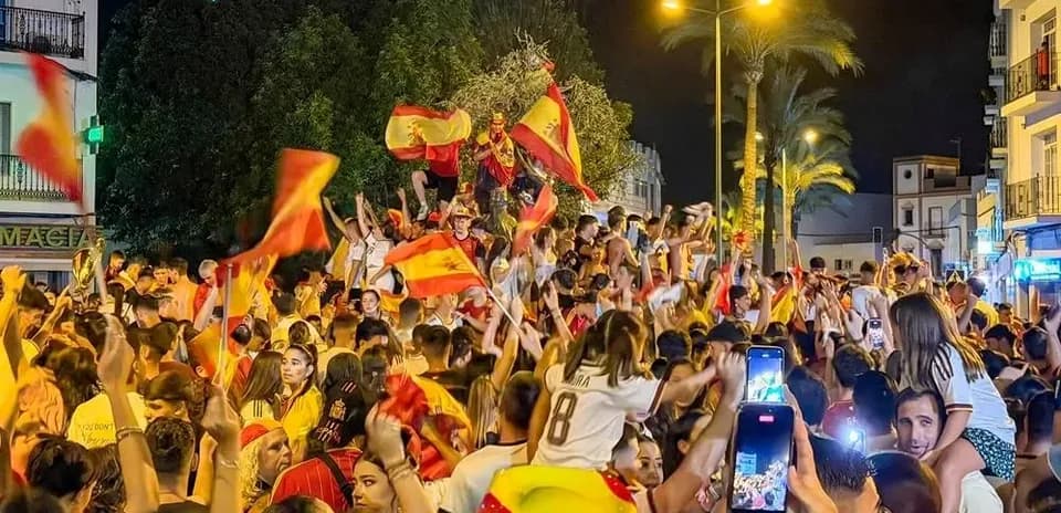 Crowd celebrating with flags in a street at night