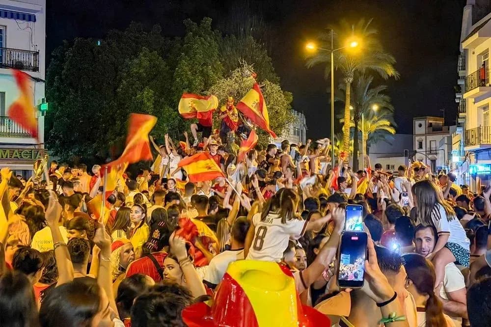 Crowd celebrating with flags in a street at night