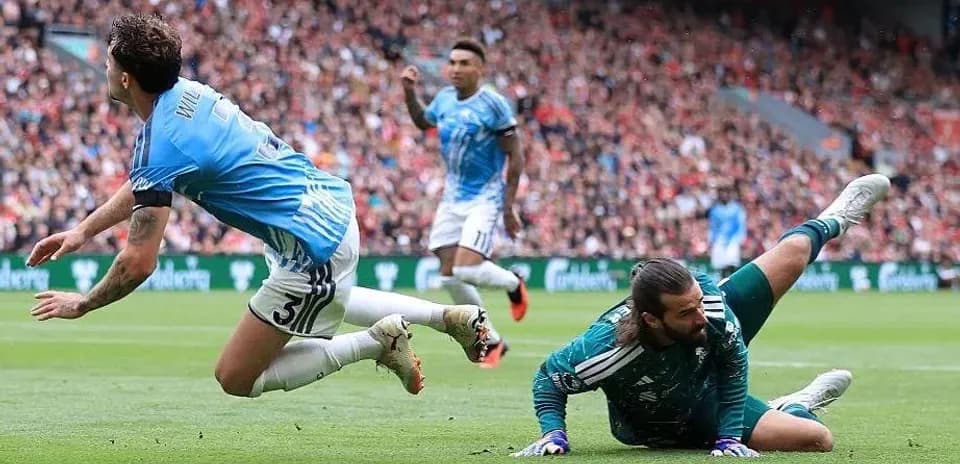 Player sliding past goalkeeper during a match