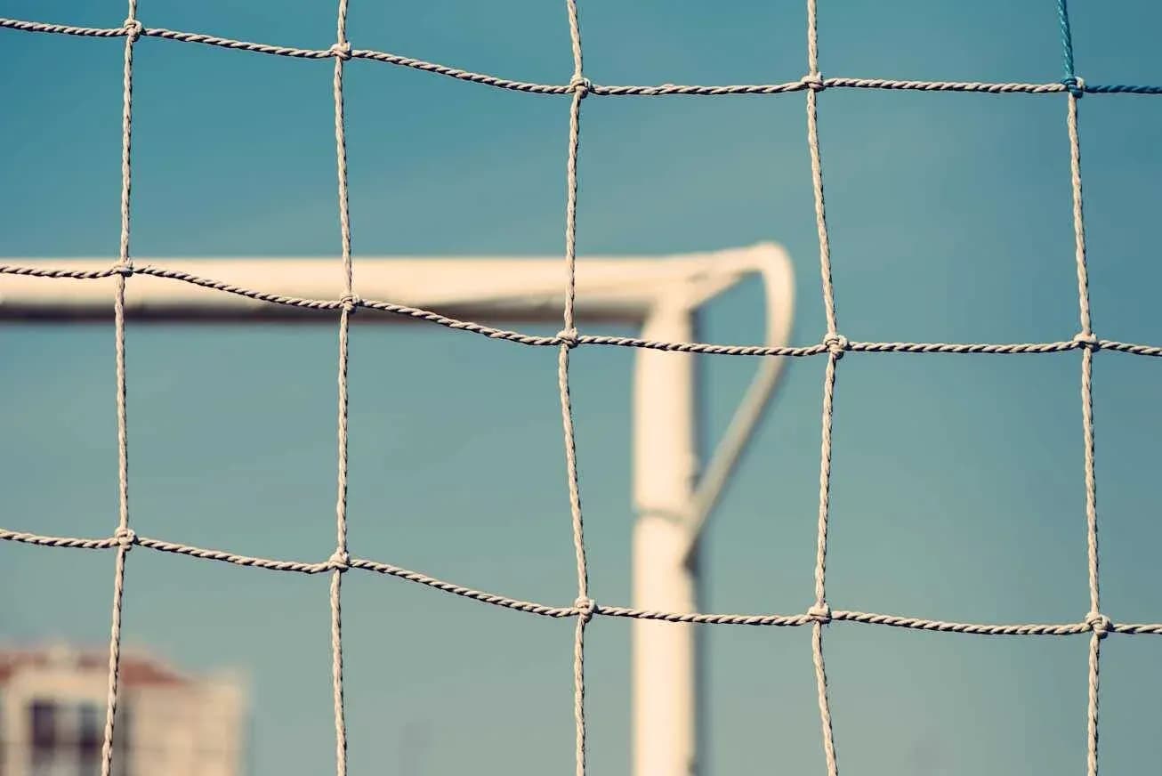 Close-up of soccer goal net against blue sky