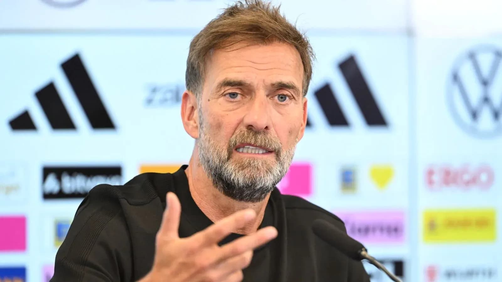 Manager speaking at press conference with microphones