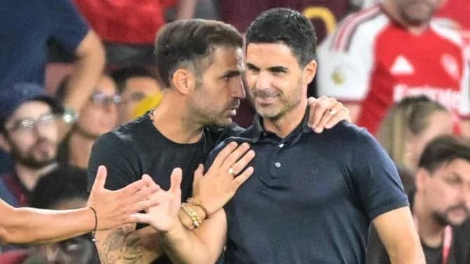 Two coaches engaged in conversation on the sidelines