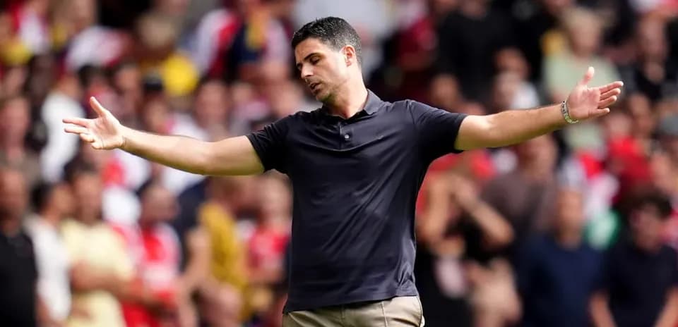 Manager gesturing during a match with fans in background