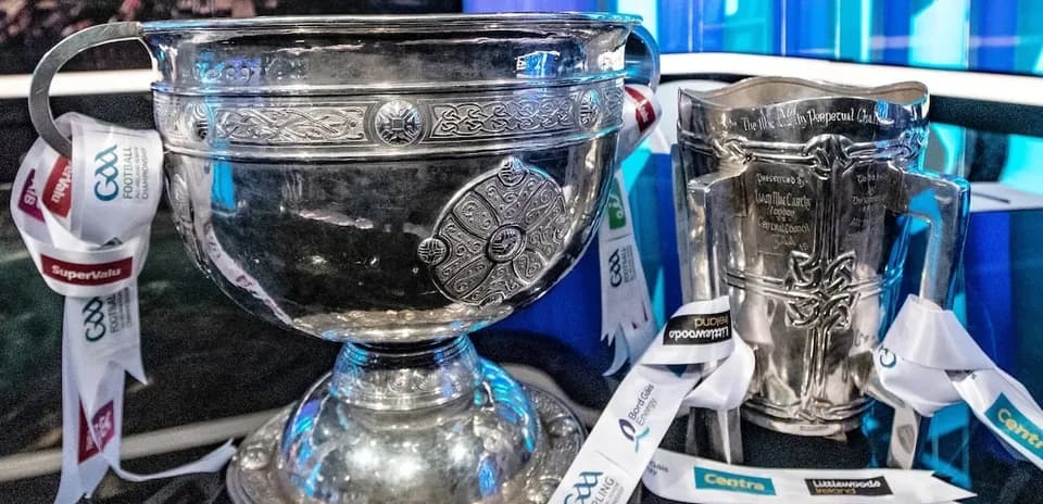 Two silver trophies with ribbons displayed on table