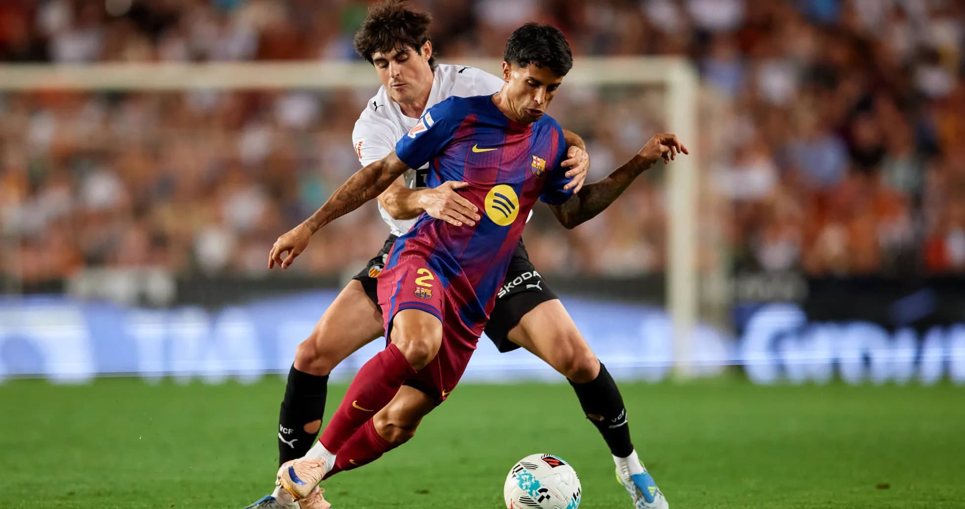 Barcelona player challenged by Valencia opponent during match