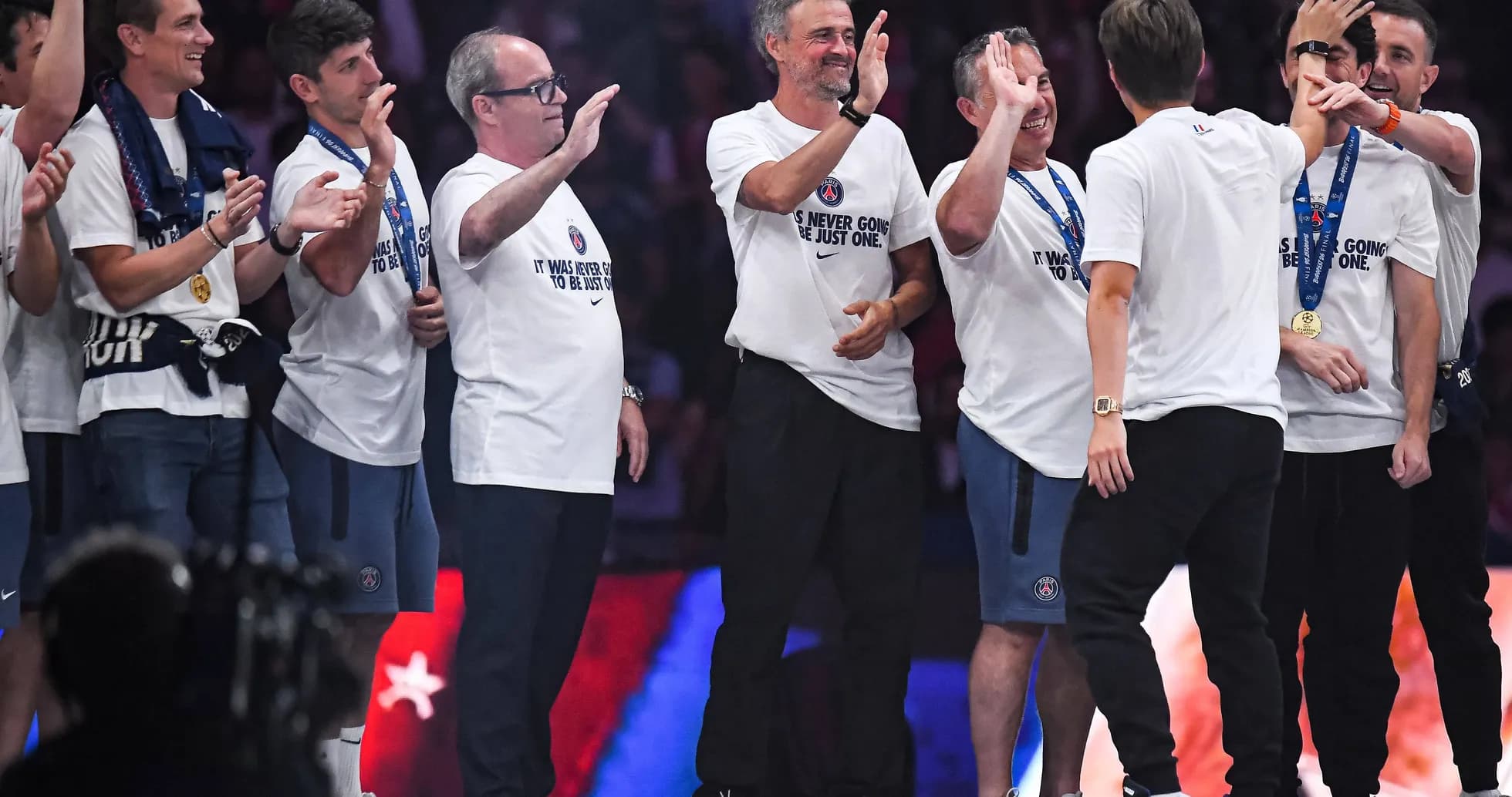 Coaches and staff celebrating on stage with medals