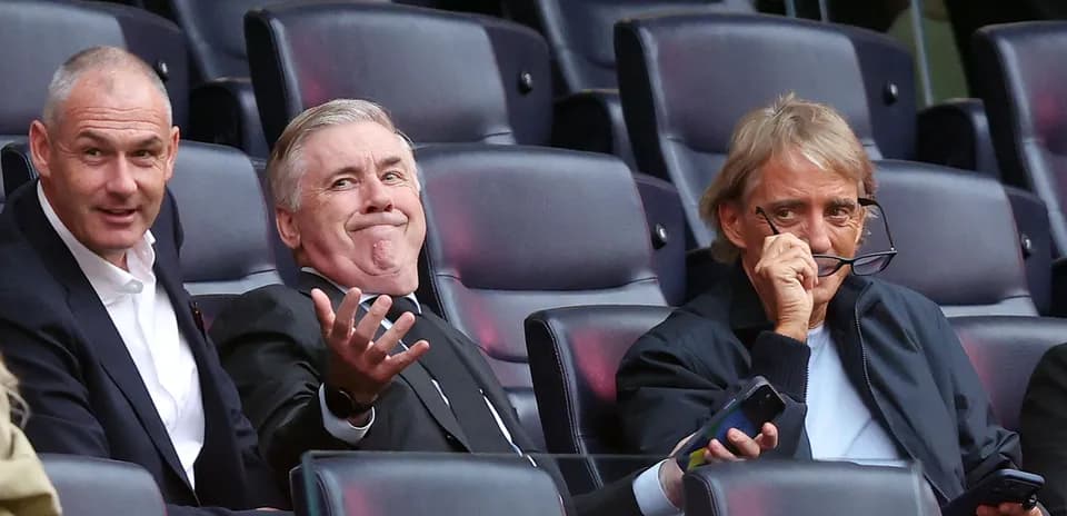 Three men seated in stadium, discussing match