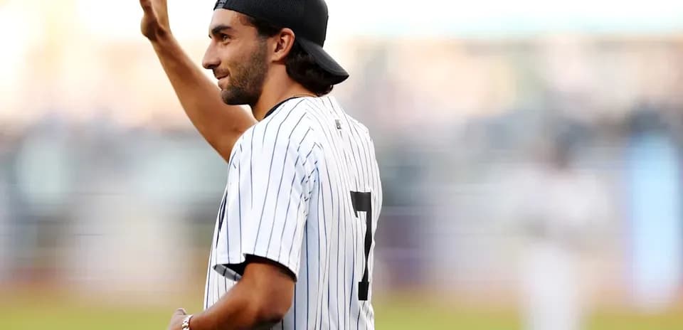 Man waving while wearing a striped baseball jersey