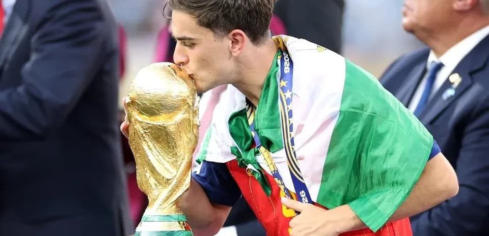 Player kissing World Cup trophy while wrapped in flag