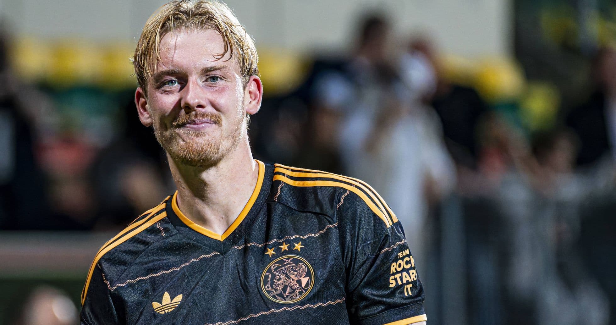 Football player in Ajax jersey smiling after match
