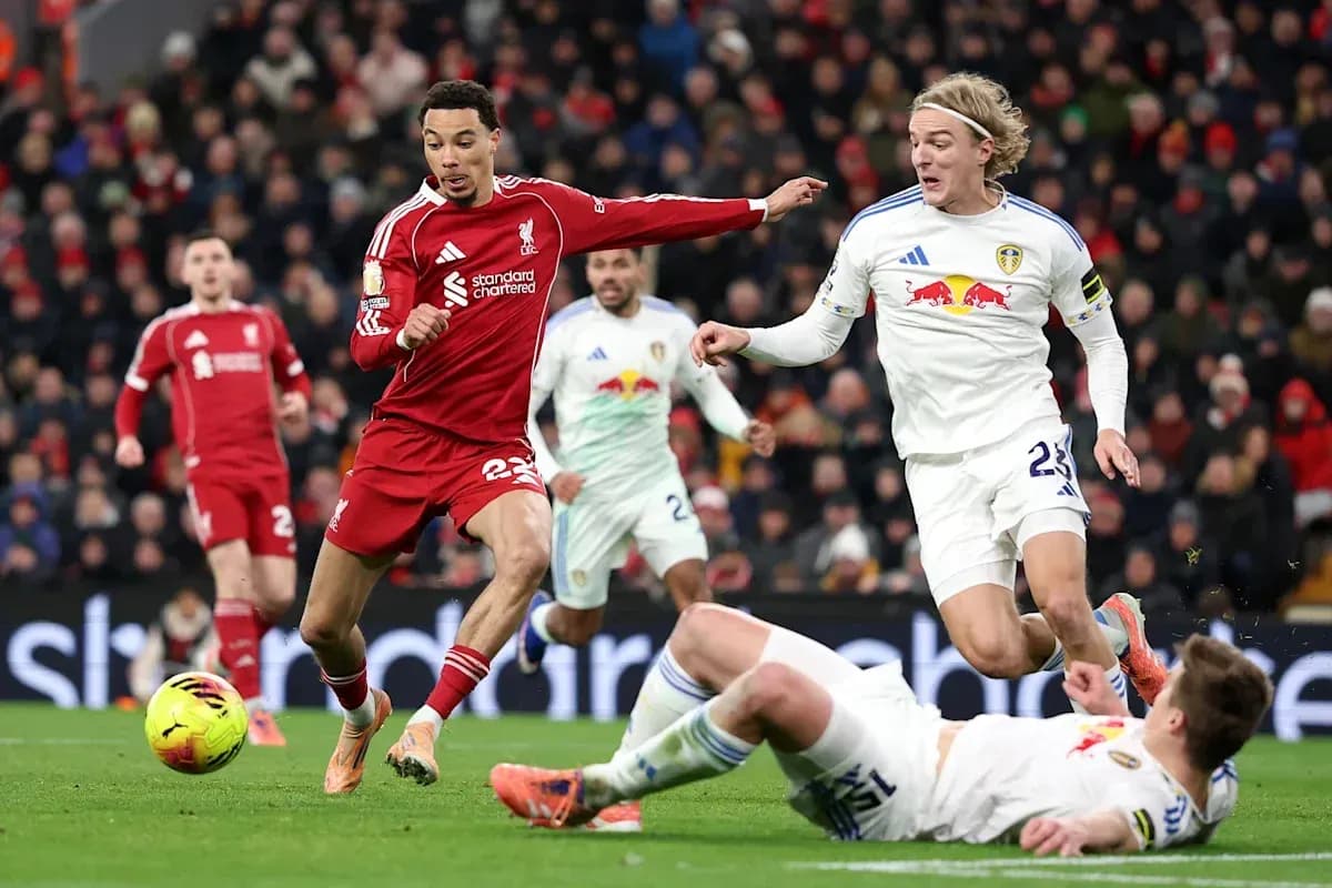 Liverpool player dribbling past Leeds defenders on pitch