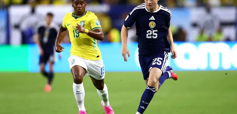 Player in blue jersey dribbling ball, pursued by opponent