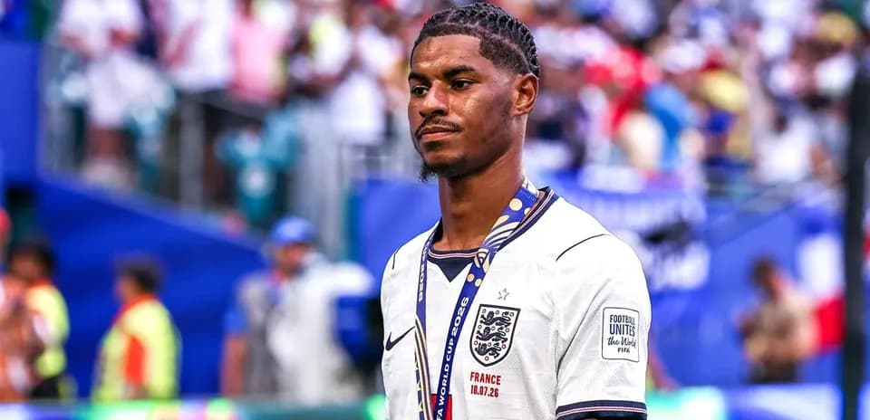 Player in England jersey with medal on pitch
