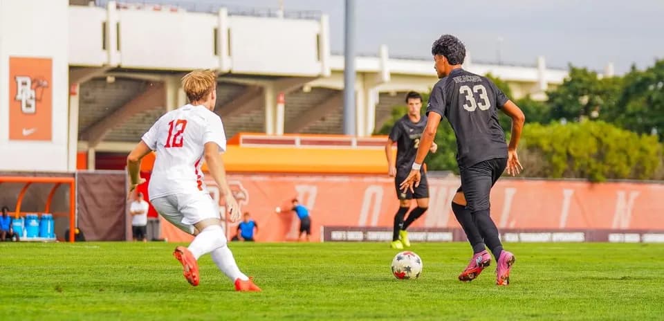 Player in black dribbling ball against opponent in white