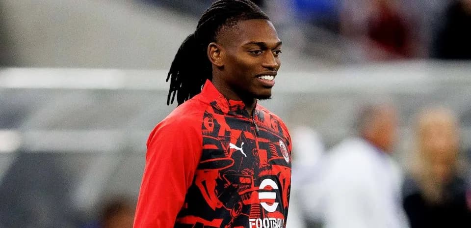 Player in red warm-up jacket smiling during training