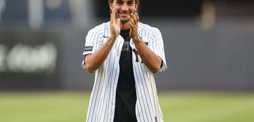 Man in Yankees jersey applauding at baseball field