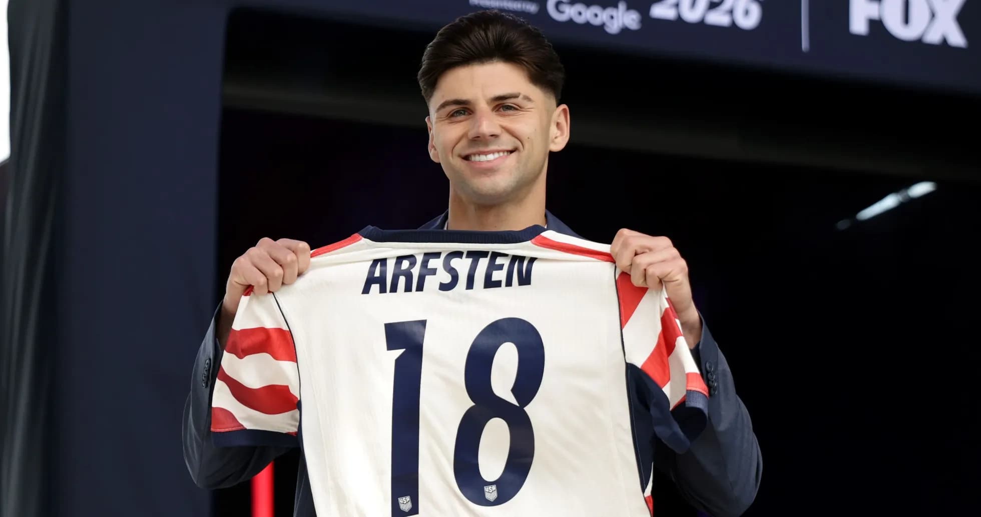 Player holding up jersey with name Arfsten and number 18