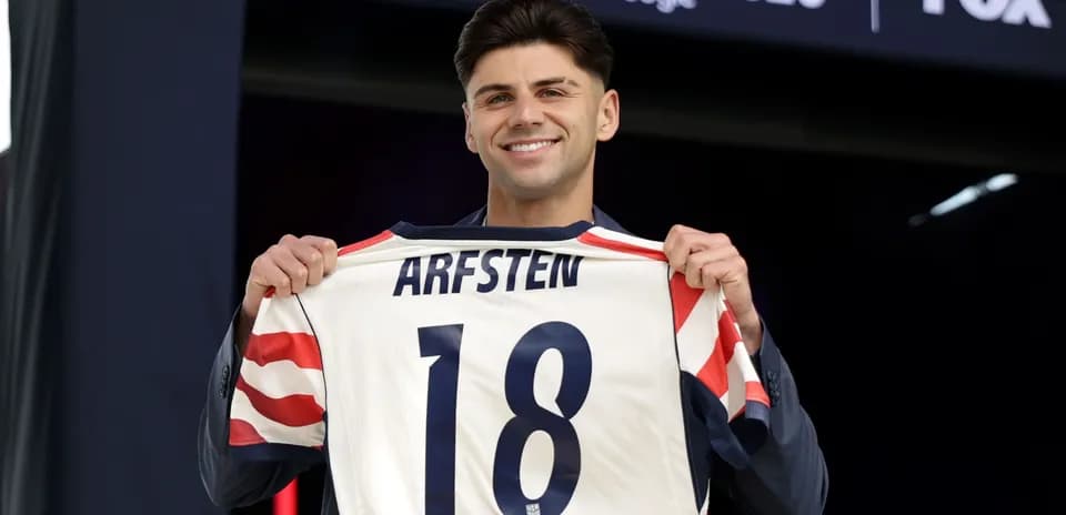 Player holding up jersey with name Arfsten and number 18