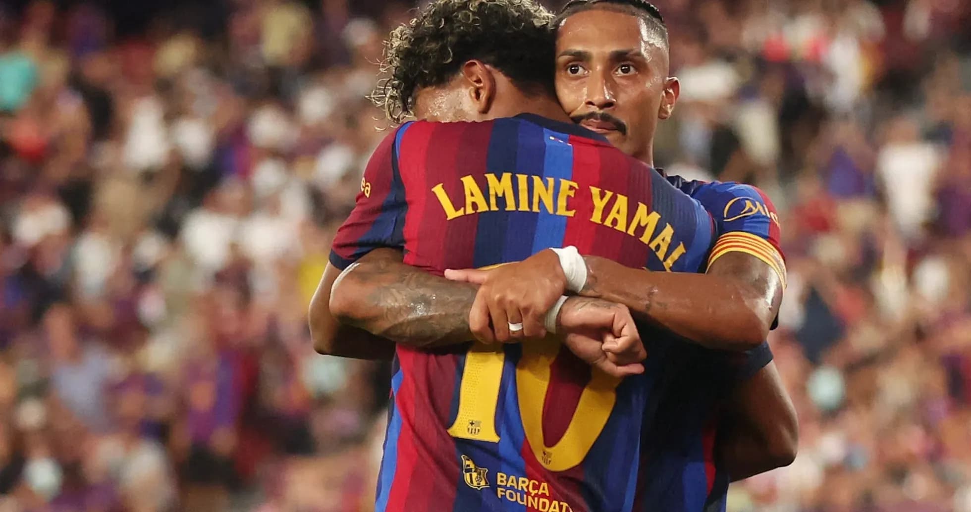 Two FC Barcelona players embracing on the field
