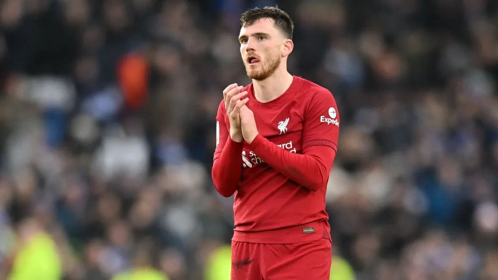 Player in Liverpool jersey applauding crowd