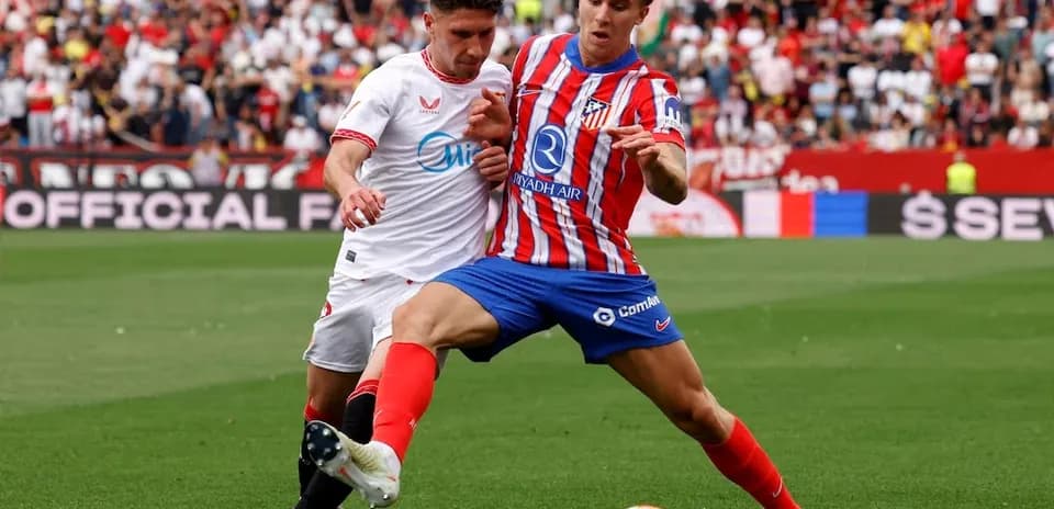 Sevilla player tackles Atletico Madrid opponent