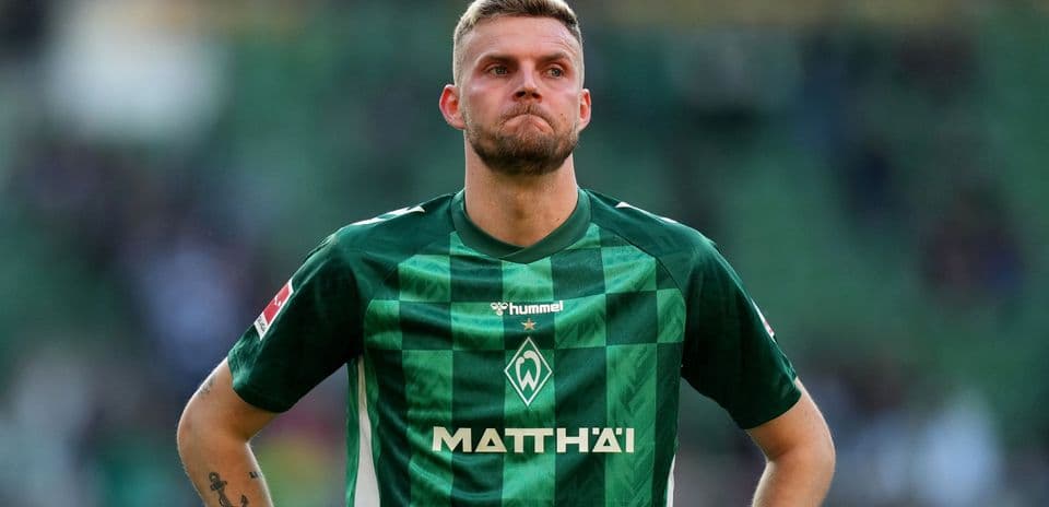 Player in green jersey looking down on the pitch