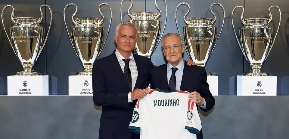 Mourinho holding a jersey with trophies in background