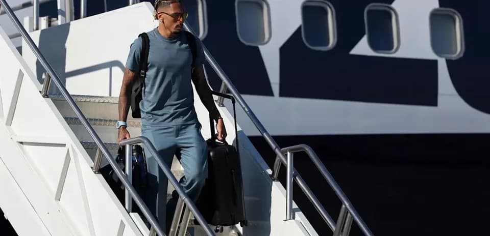 Player descending airplane steps with luggage