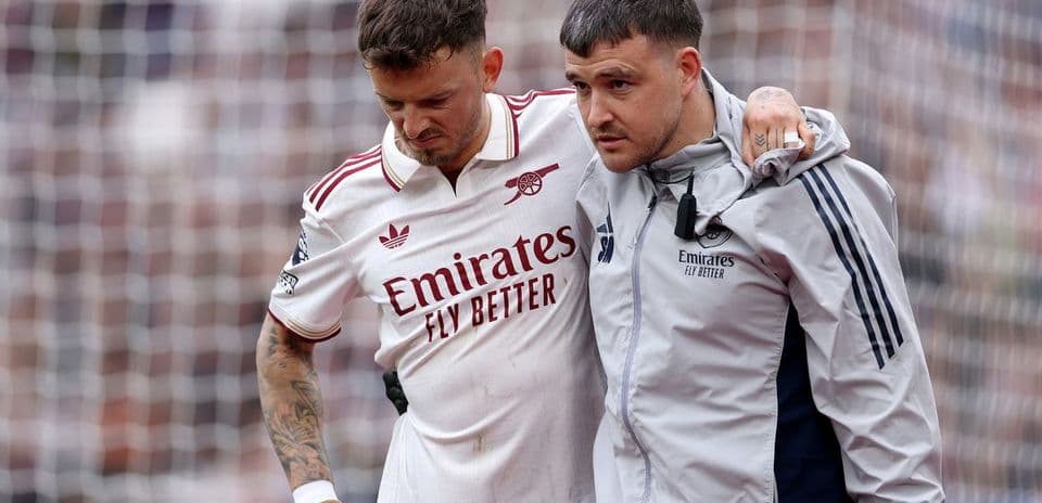 Player being assisted off the pitch by staff