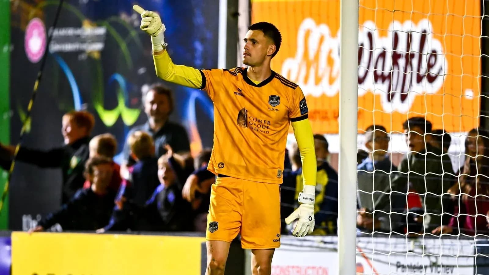Goalkeeper signaling during a match with fans in background