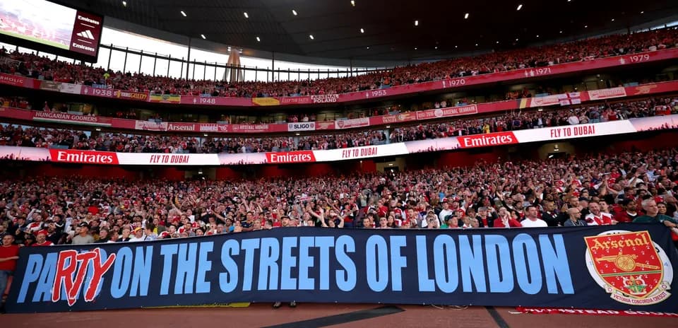 Arsenal fans holding banner in stadium crowd