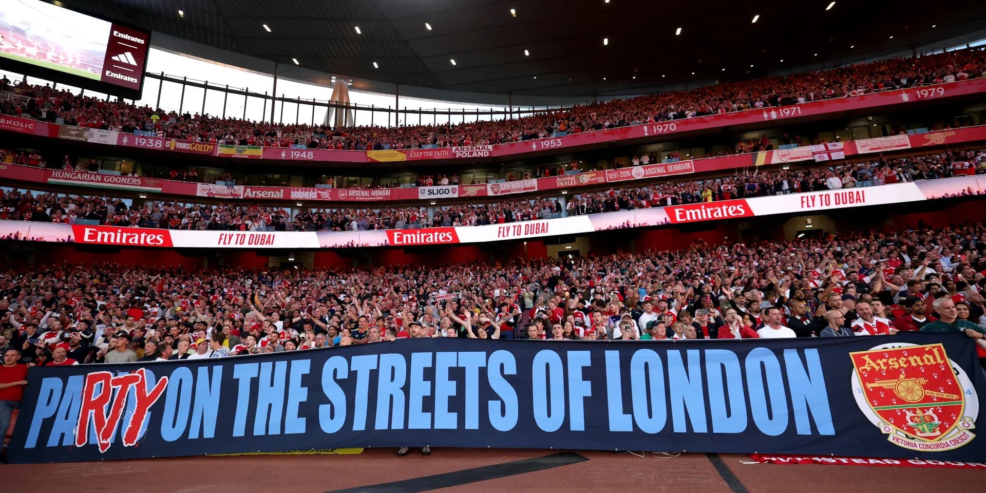 Arsenal fans holding banner in stadium crowd