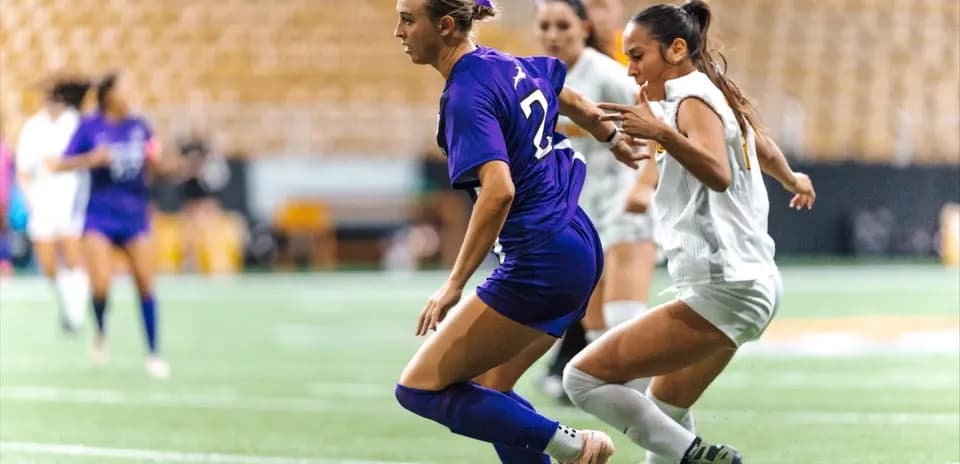 Two female players competing for the soccer ball