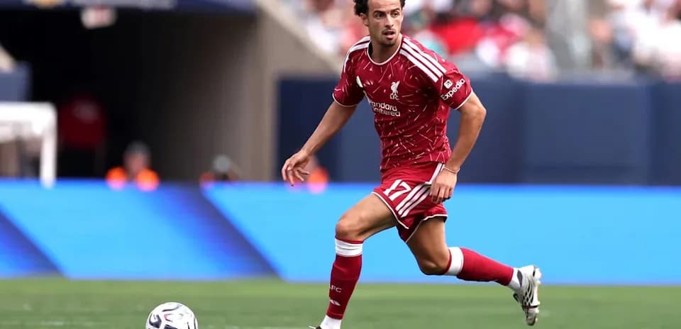 Player in Liverpool kit running with soccer ball