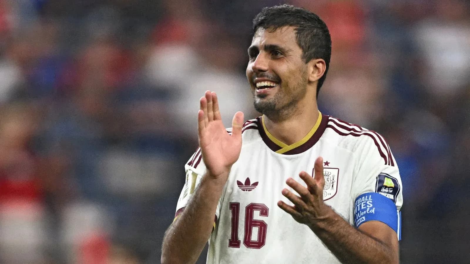 Player in Spain jersey applauding fans after match