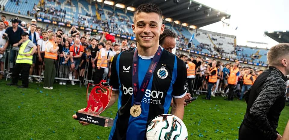 Player celebrating with trophy and ball on field