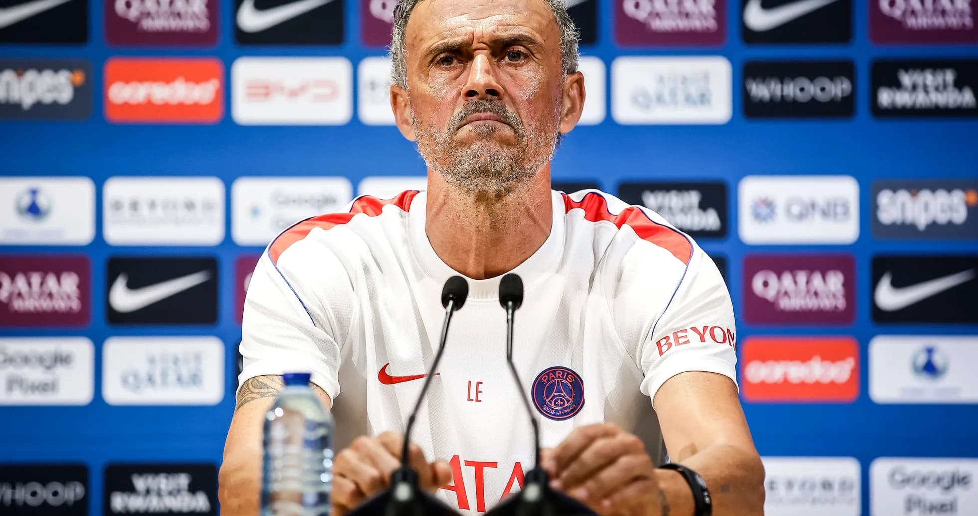 Manager at press conference with team branding backdrop