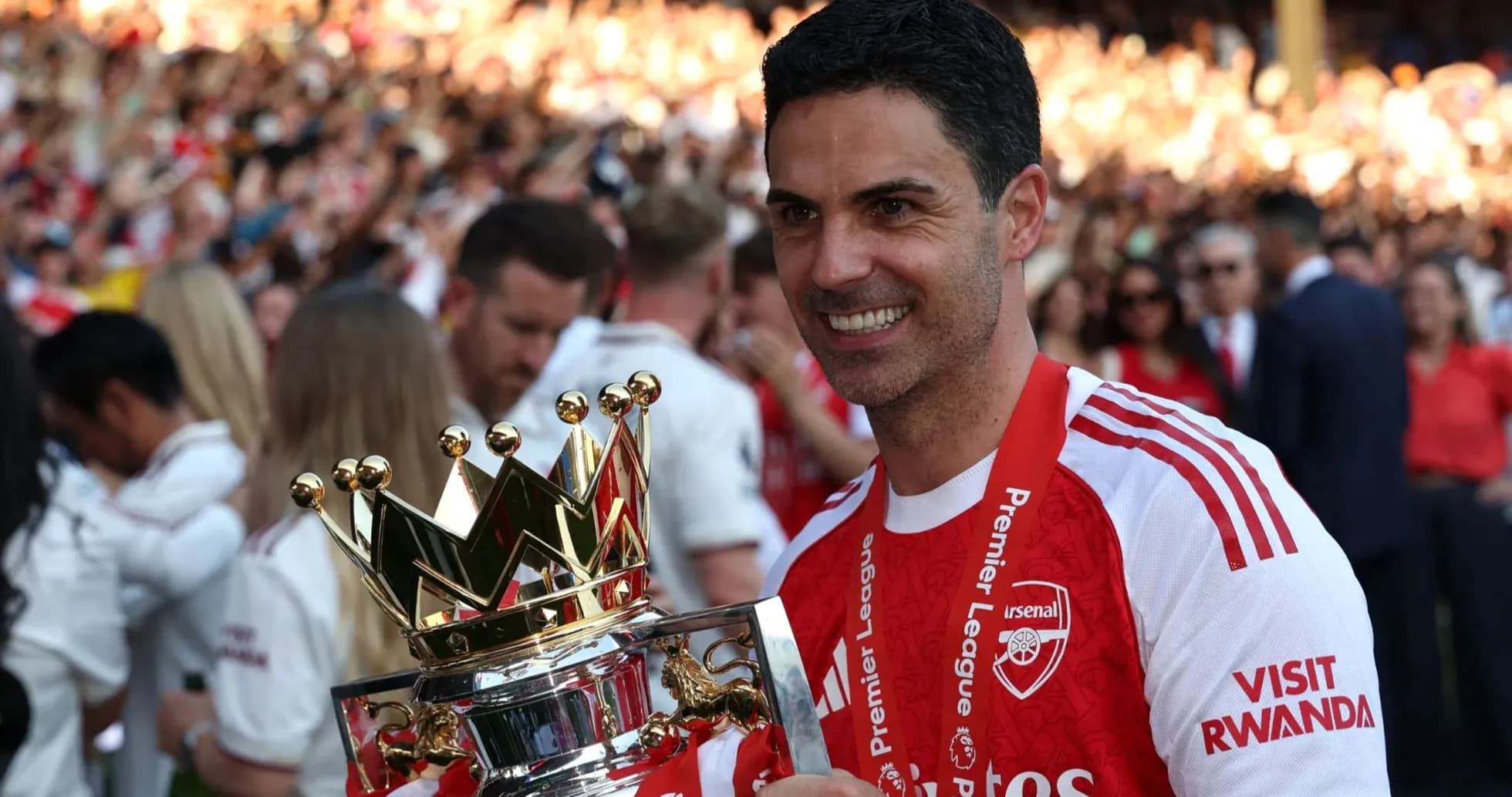 Arsenal manager holding Premier League trophy on pitch