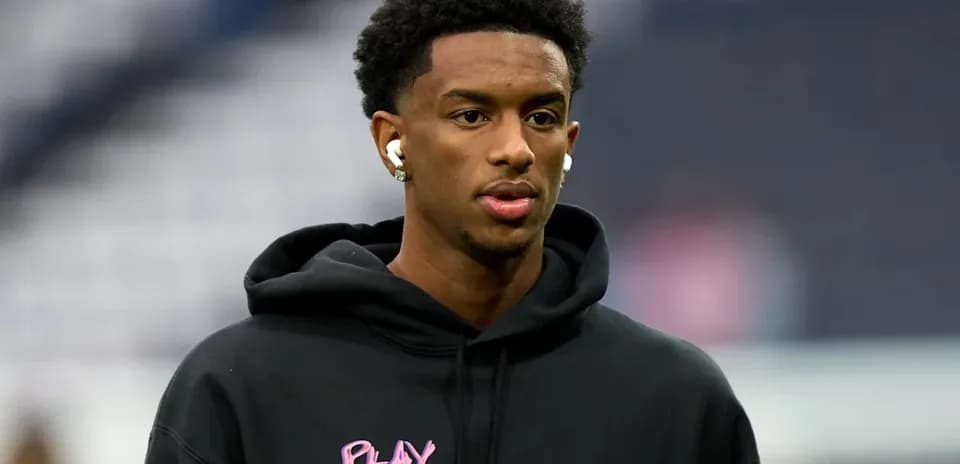 Player wearing earbuds in black hoodie before game